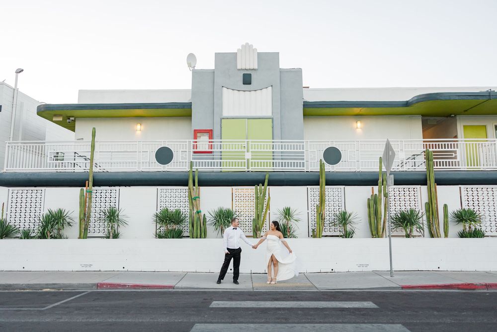 Modern school building exterior with white walls, green accents, and desert landscaping features tall cactus plants.