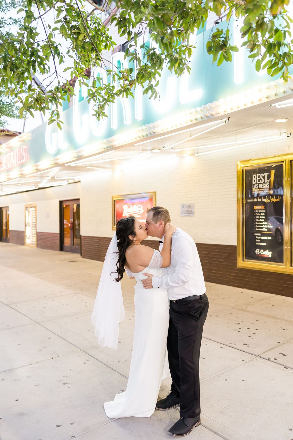 A romantic wedding photo series showing a couple in front of a brick wall with trees overhead.