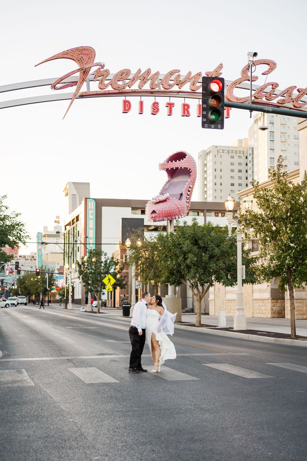 Couple walking hand in hand under vintage Fremont Street District sign in downtown Las Vegas at sunset.