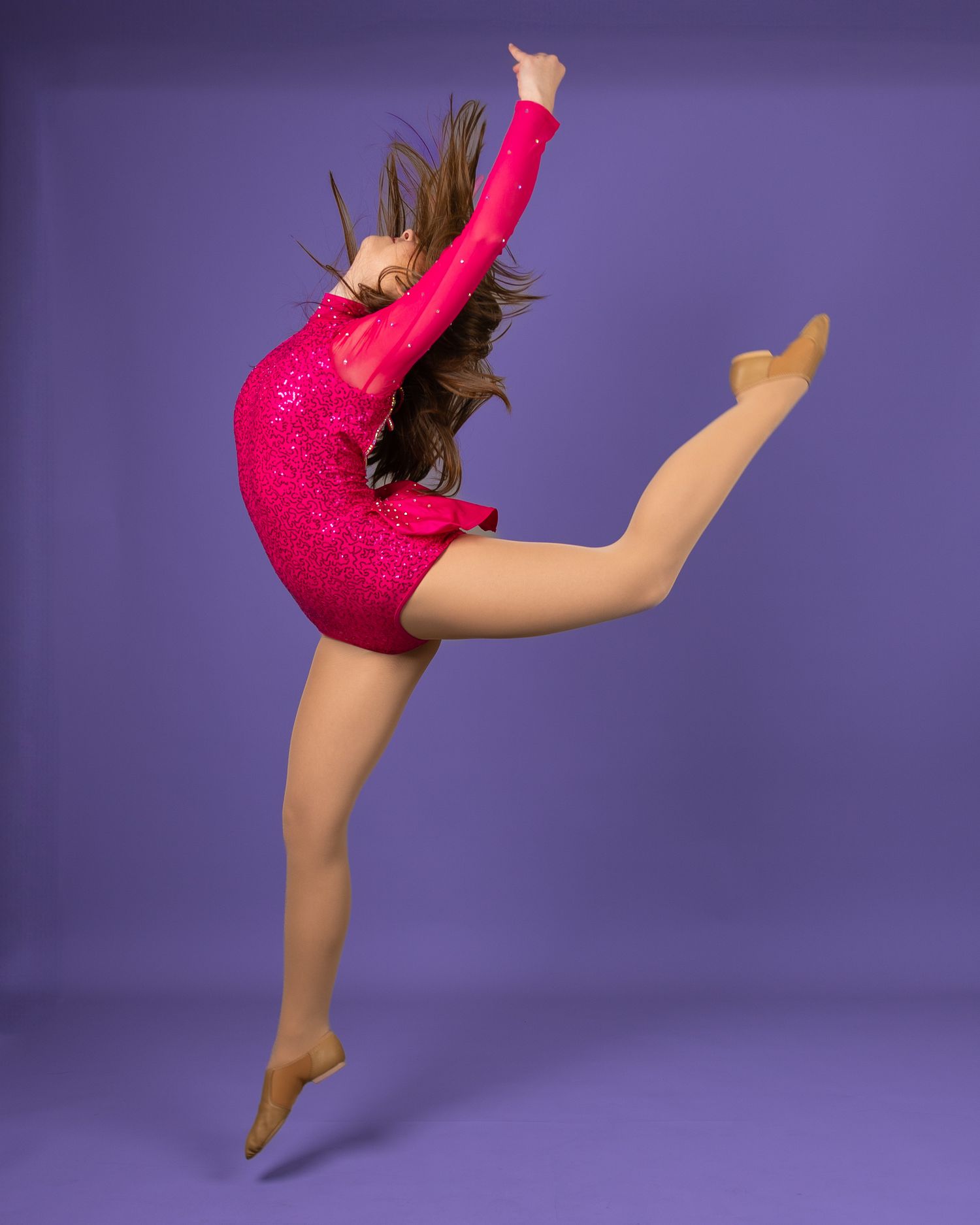 A gymnast in a sparkly pink leotard performs a dynamic split leap against a purple background.