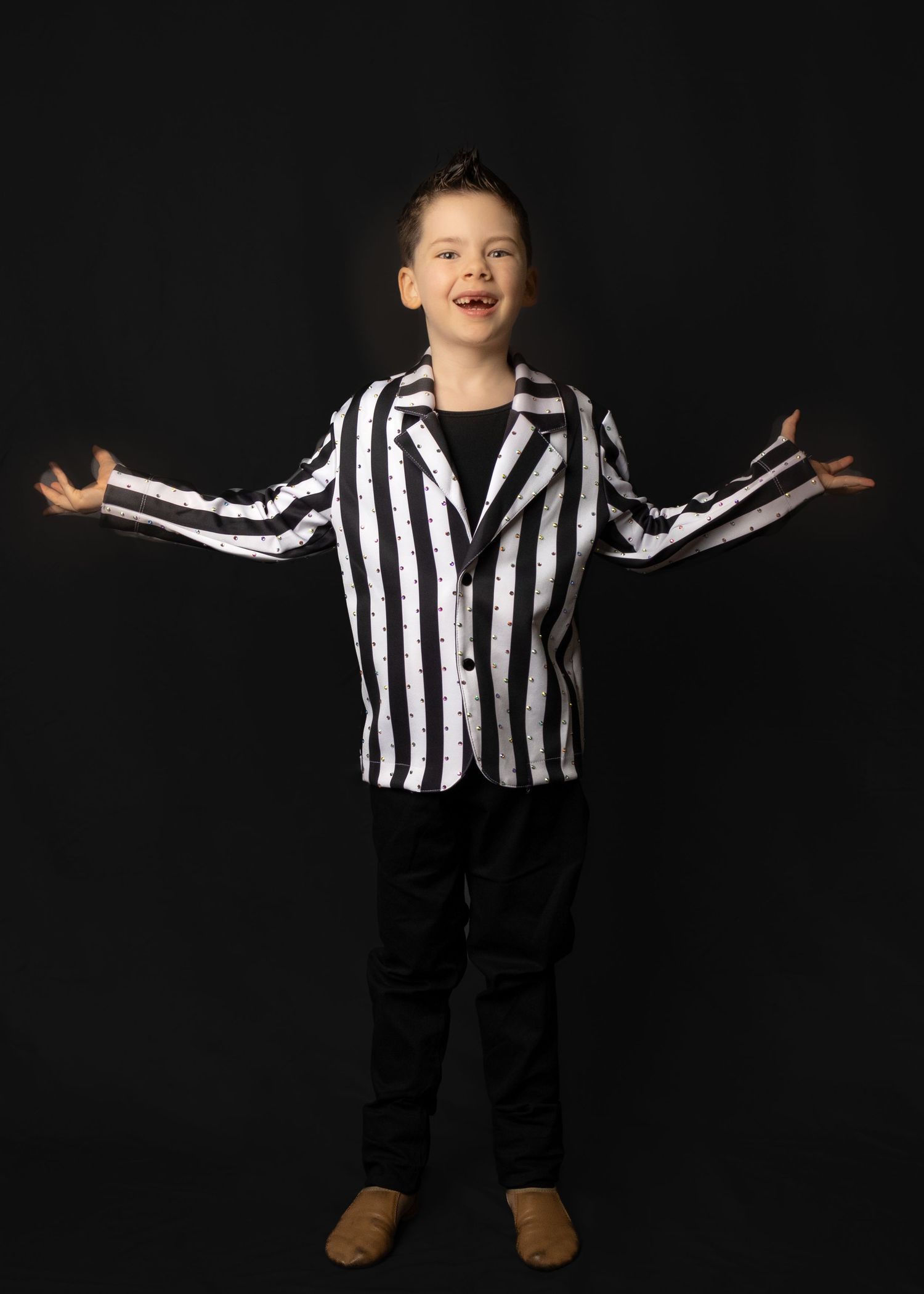 A striped black and white jacket with black pants in a joyful pose against a dark background.