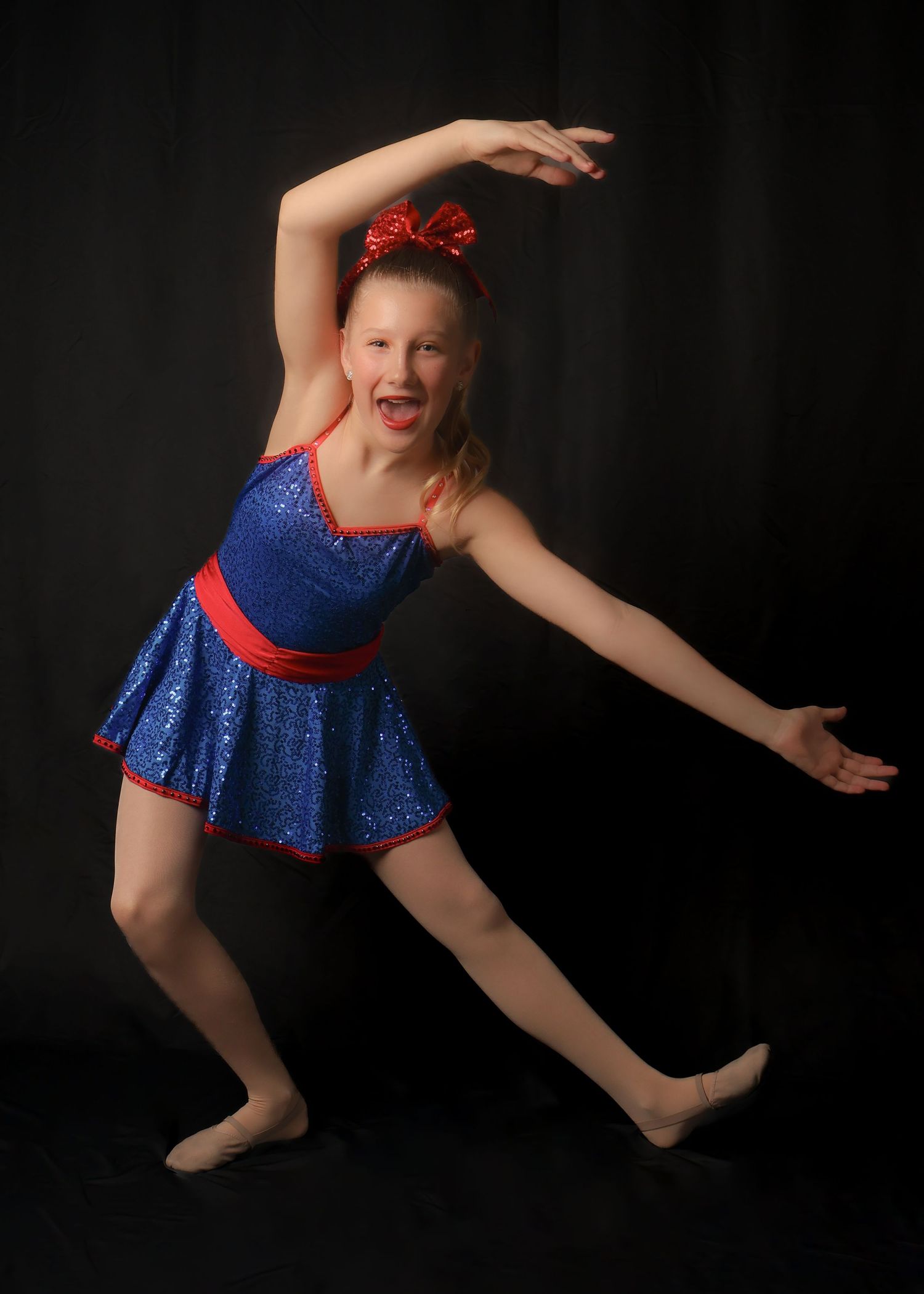 A dancer in a sparkling blue and red costume performs a series of graceful leaping movements against a dark background.