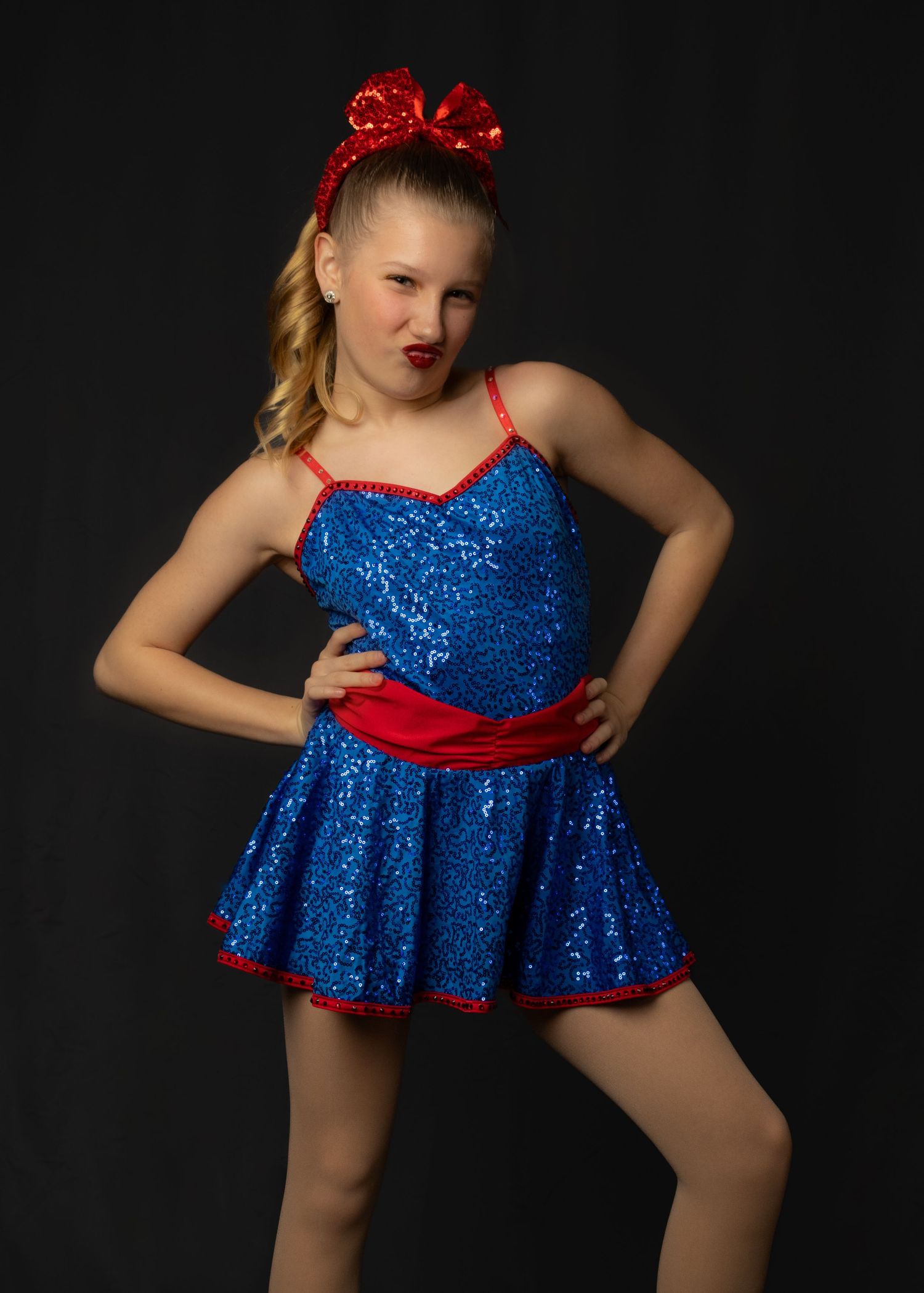 A dance costume in sparkly blue sequins with red bow accents captured against a dark background.