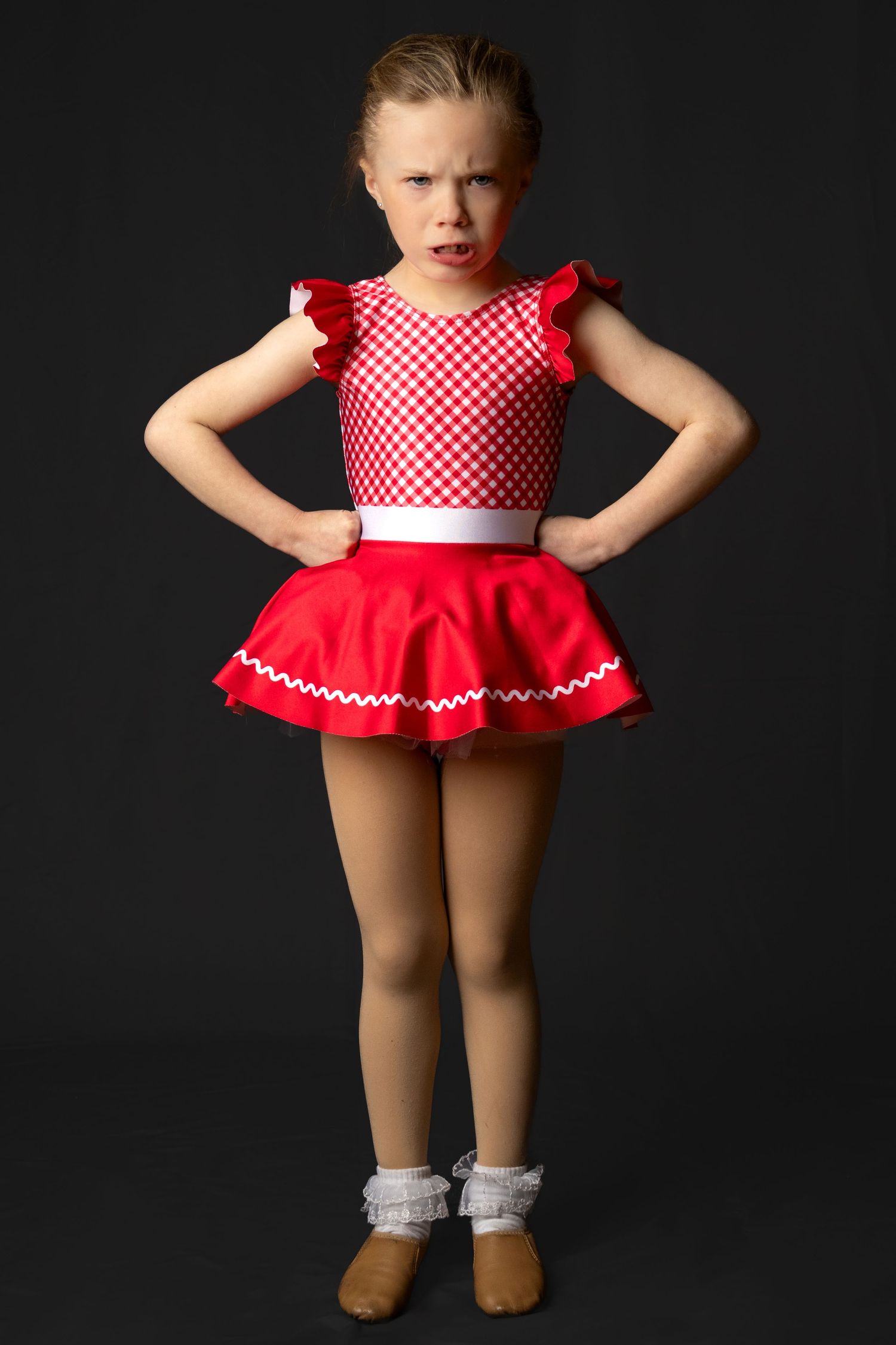 A red and white checkered dance costume with ruffled skirt and white accents shown on dark background.
