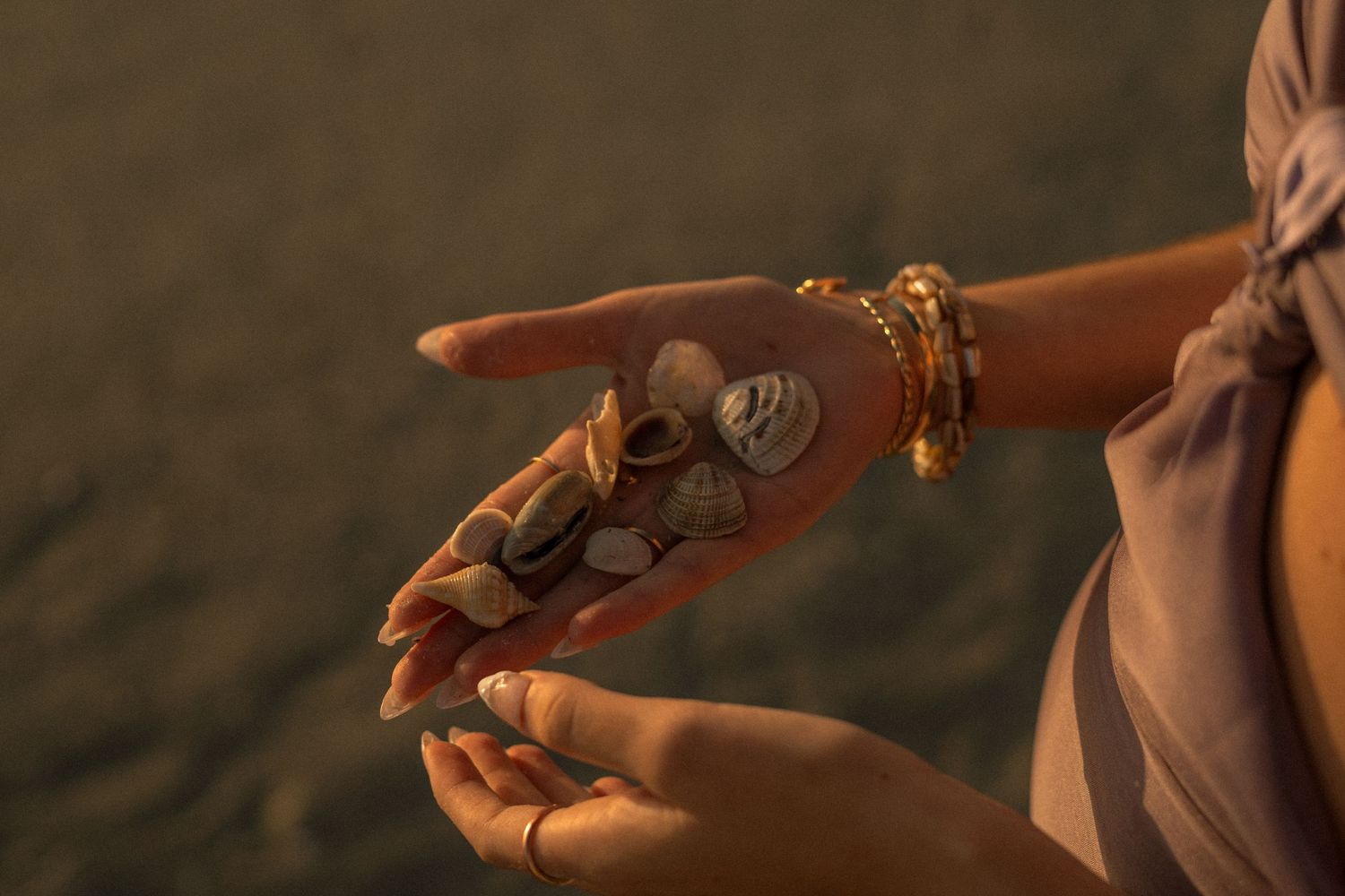 close up of f holding shells in her hand at the beach