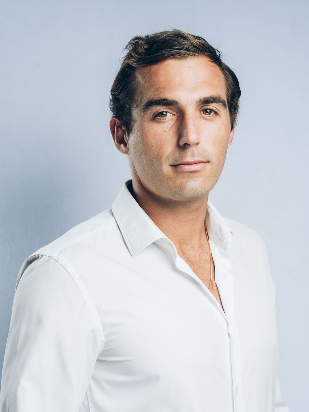 Professional headshot of a young man in a white shirt against a light gray background.