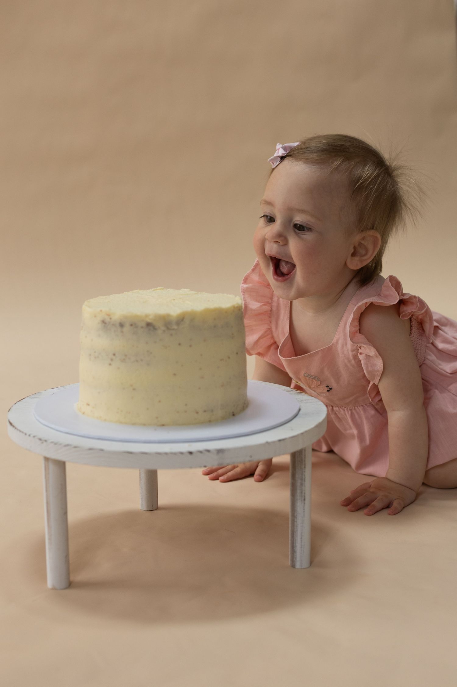 Smiling baby eating cake at cake smash photo shoot.