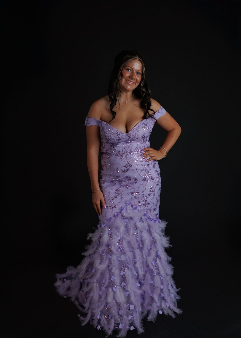 A lavender ruffle dress with dramatic feathered skirt and sweetheart neckline shown against a black background.