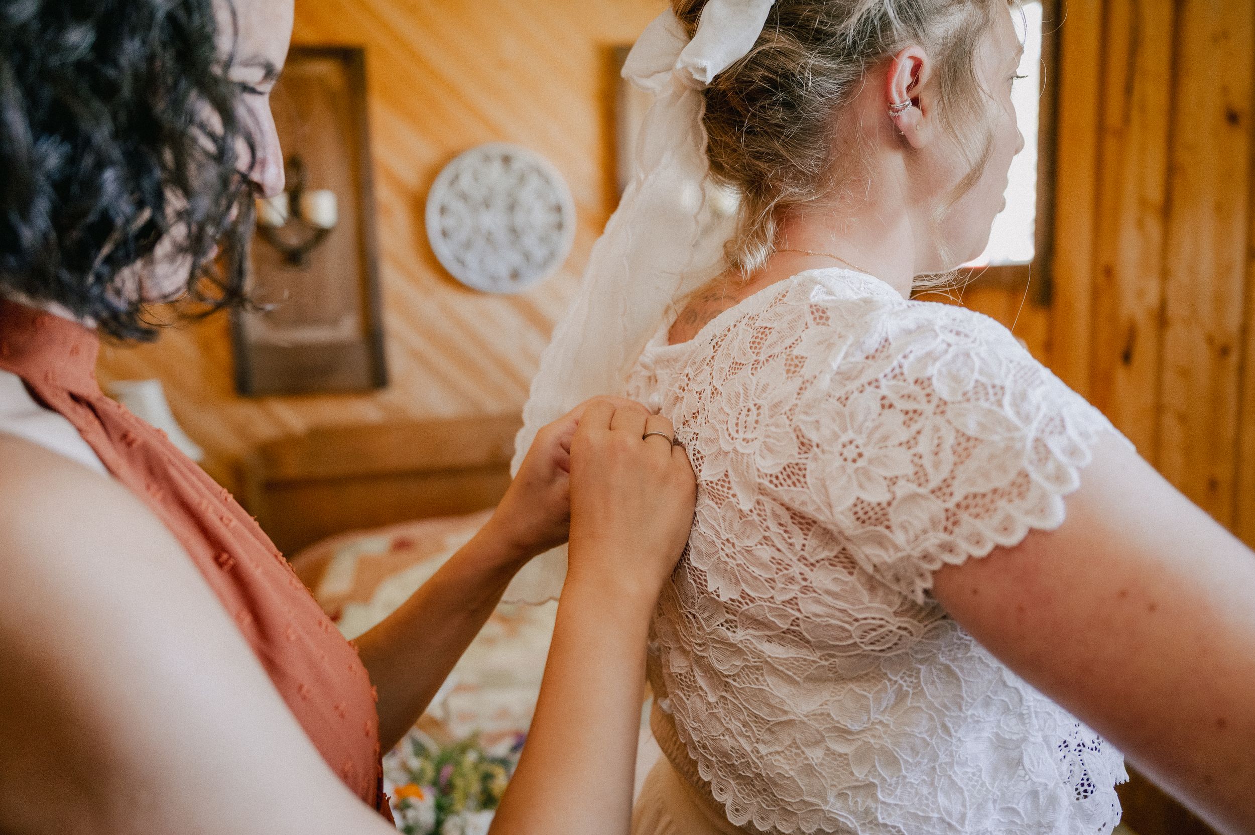 Sequence of five close-up photos showing someone helping to button up an intricate lace wedding dress detail.