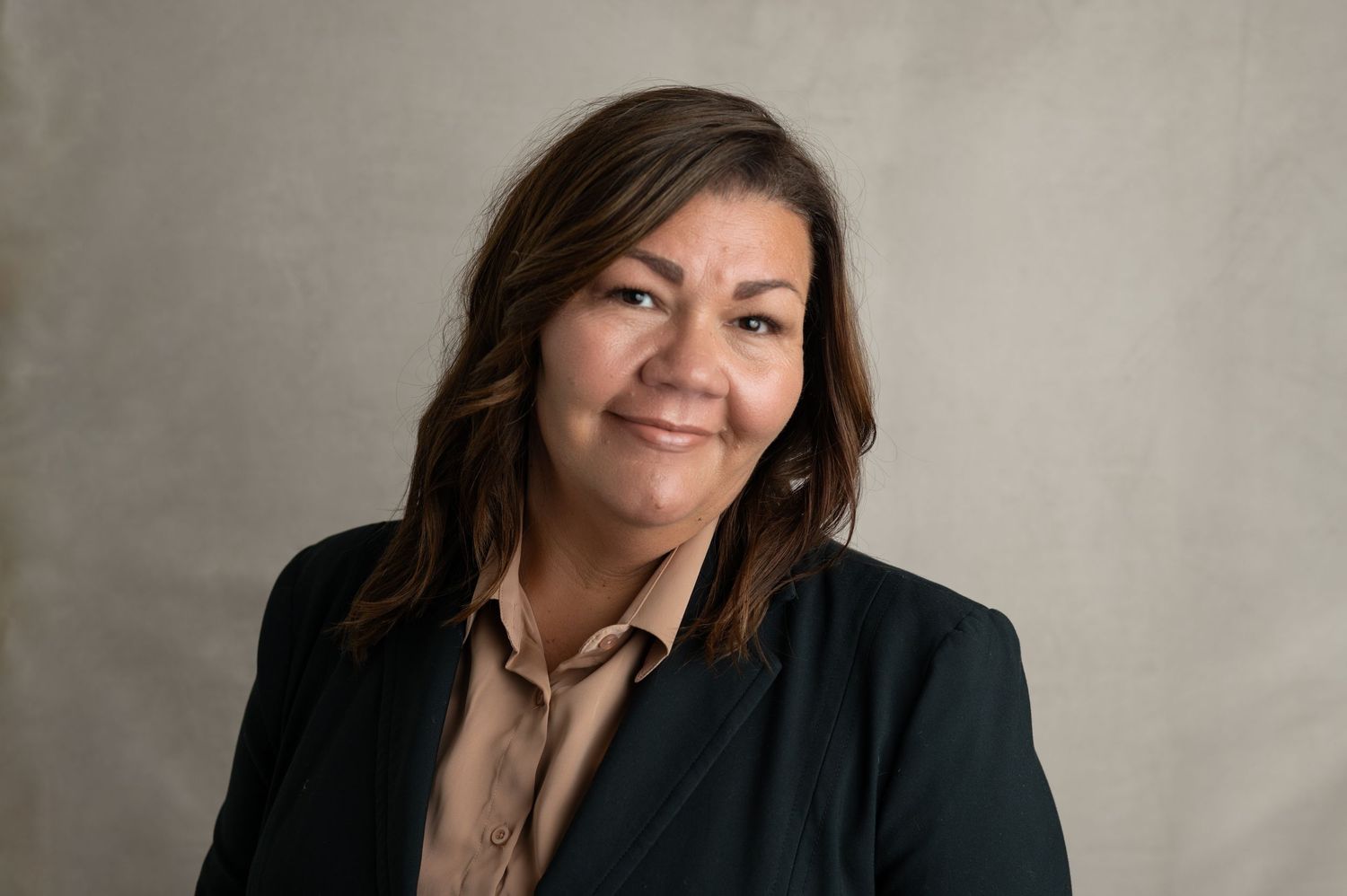 Professional headshot series showing expressions from serious to smiling against a neutral wall backdrop.