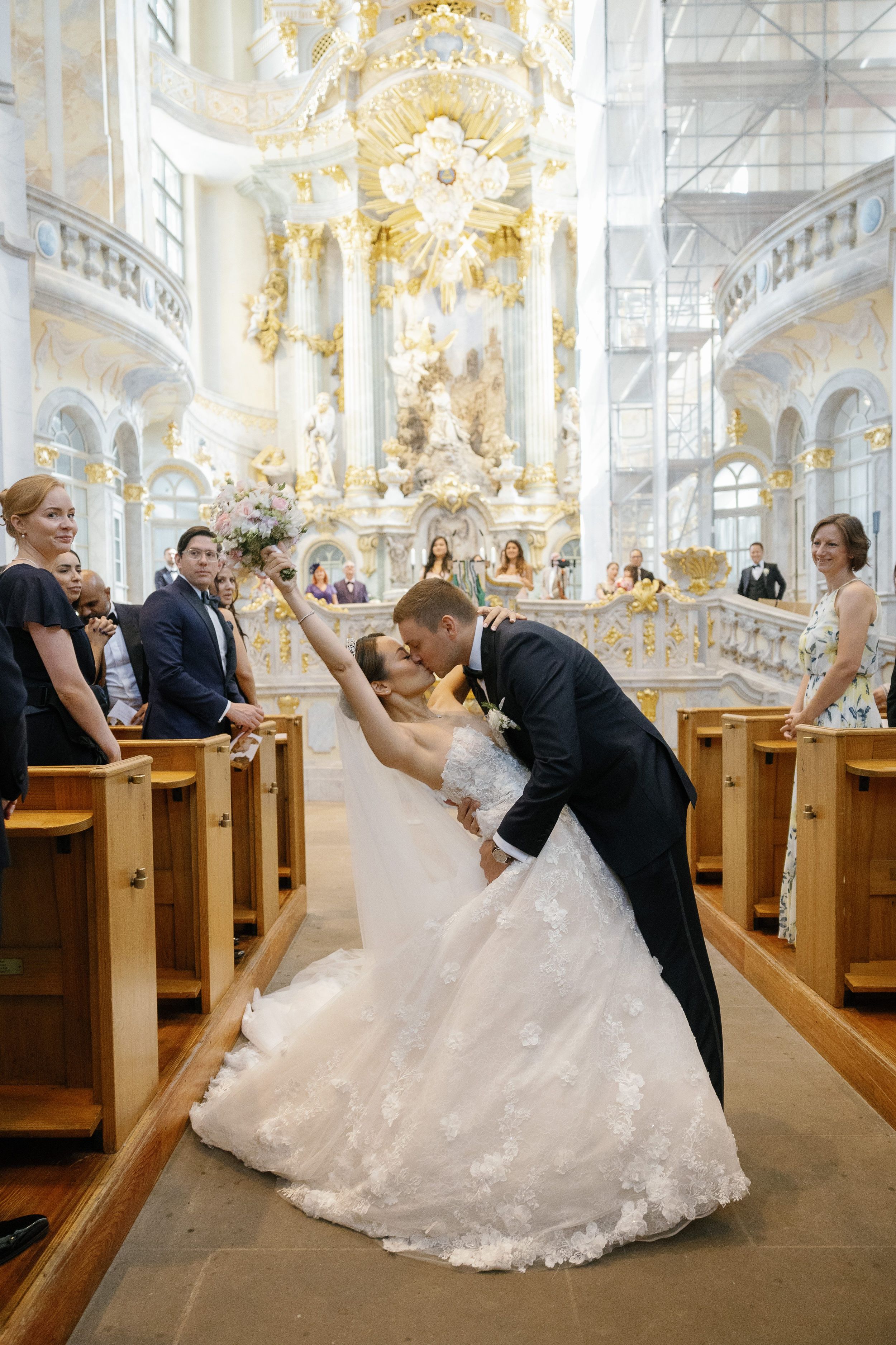 A romantic scene unfolds inside an ornate baroque church with grand chandeliers and golden decorative elements.
