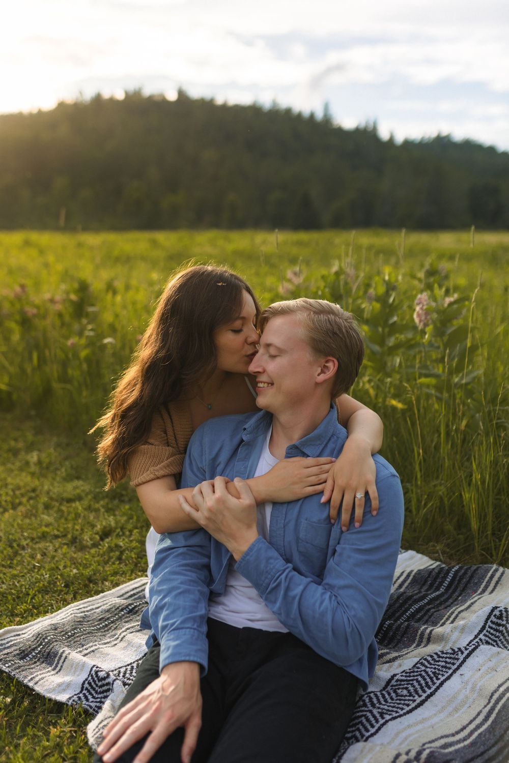 A couple shares an intimate moment on a blanket in a wildflower field.