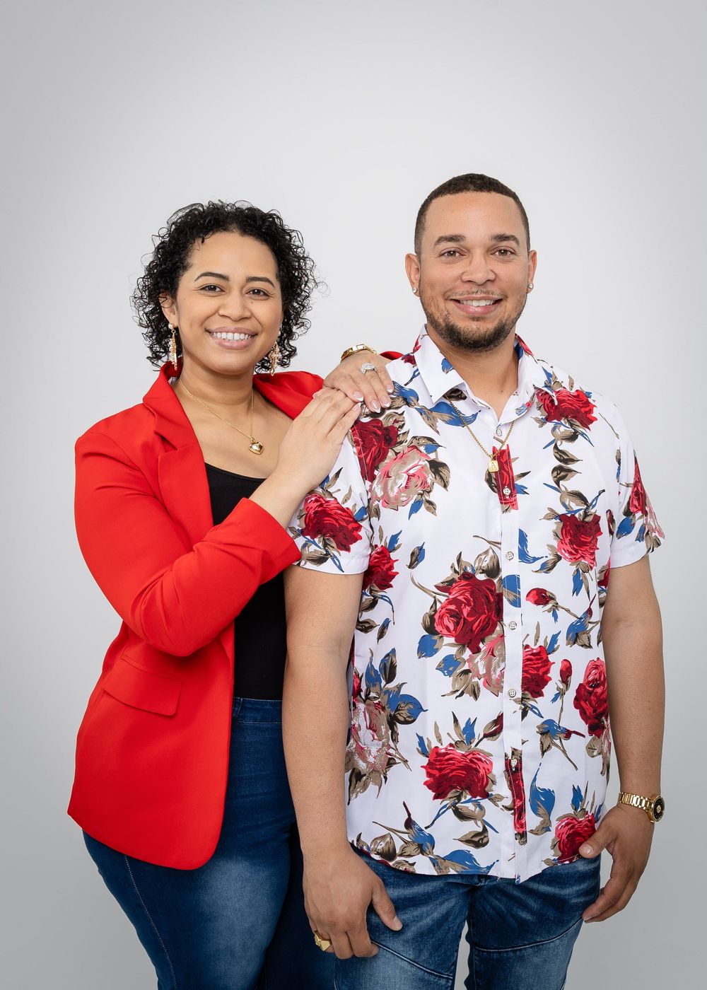 Studio portrait with red blazer and floral print shirt against light grey background.