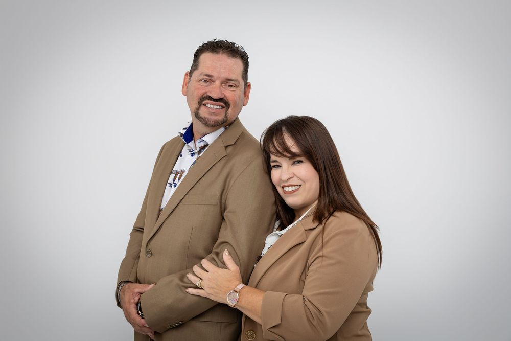 Professional studio portrait of a couple posing together against a light gray background.