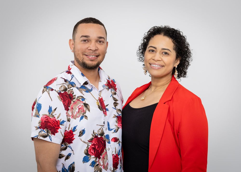 Studio portrait featuring floral print shirt and red blazer against grey backdrop.