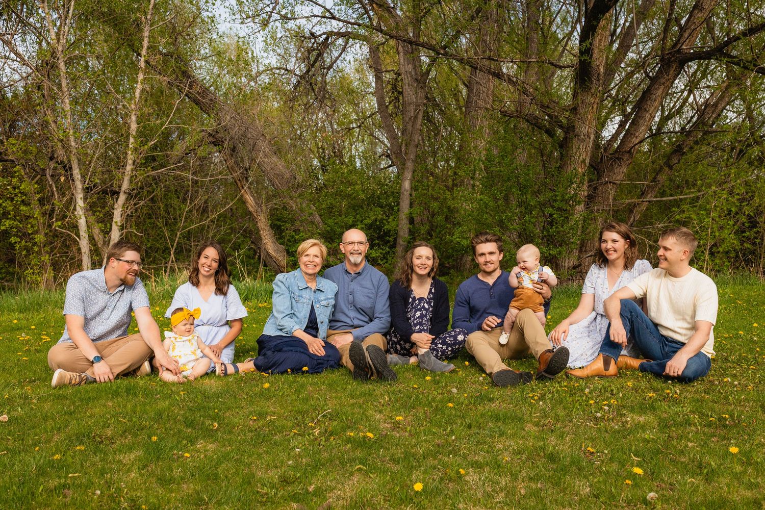 A panoramic collage of people sitting on grass in a casual outdoor setting surrounded by trees and greenery.