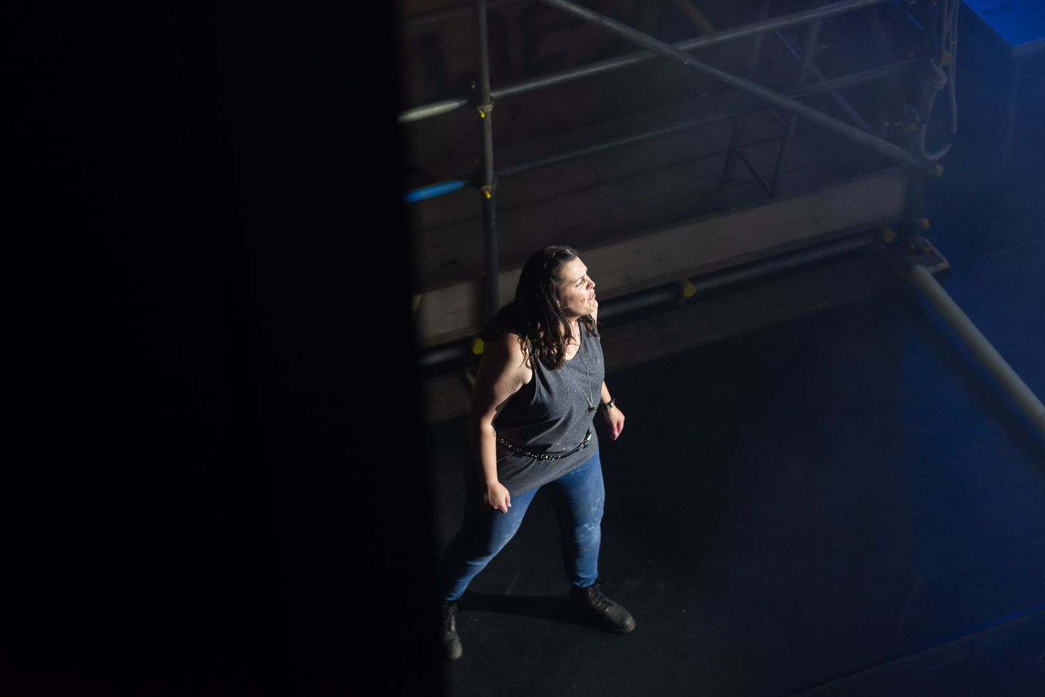 Performers in casual attire moving across a dimly lit stage area.