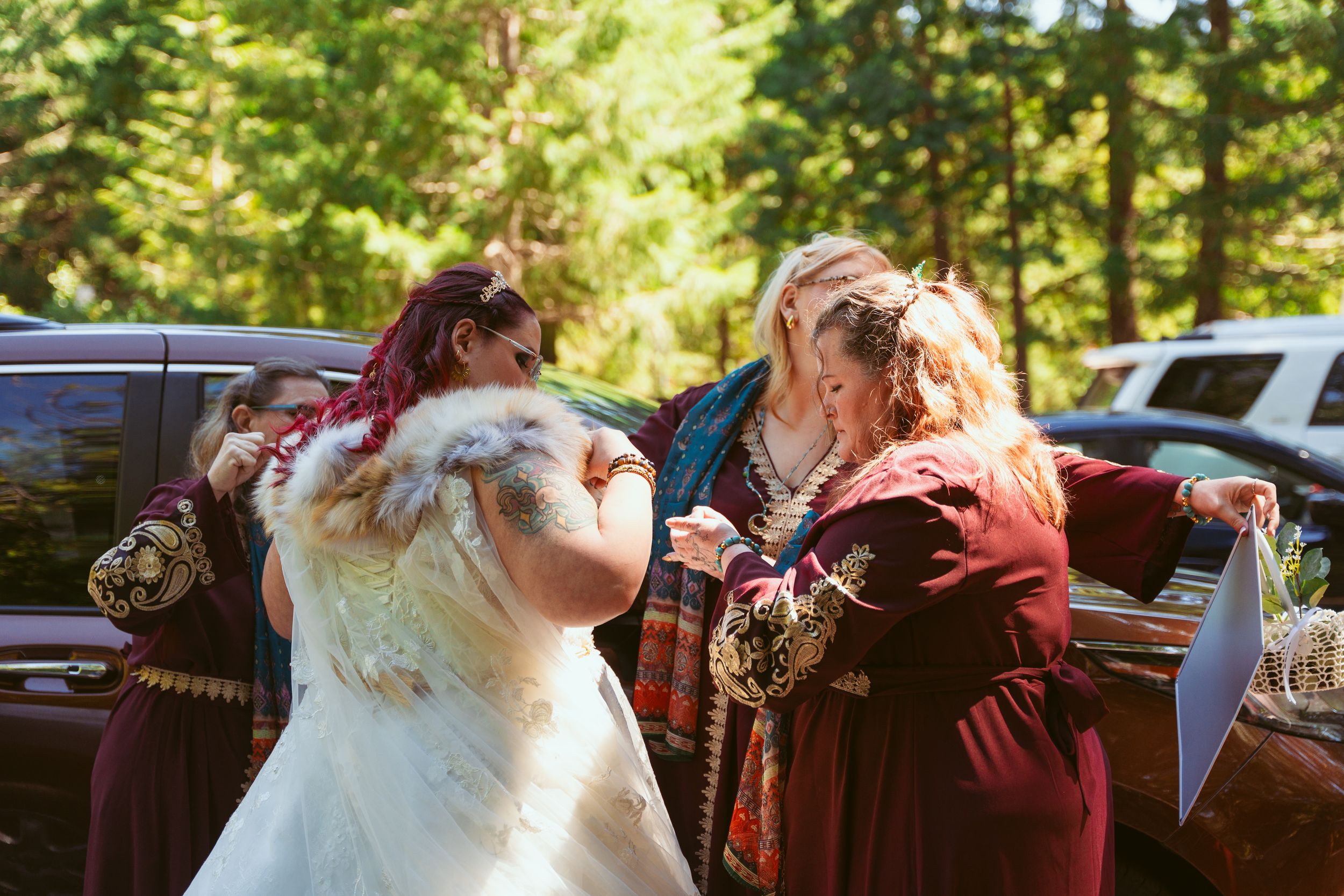 A tender candid moment is shared during a wedding celebration in front of parked cars.