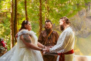 An intimate forest wedding ceremony unfolds with warm sunlight filtering through the evergreen trees.