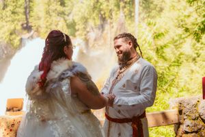 Wedding celebration participants in traditional dress interact during an outdoor forest ceremony.