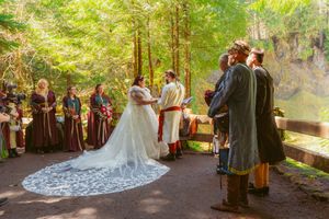 A fantasy-inspired woodland wedding ceremony features guests in period costumes and a dramatic lace wedding gown.