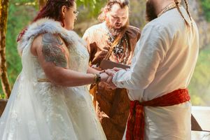 Wedding ceremony participants exchange rings during medieval-themed outdoor celebration.