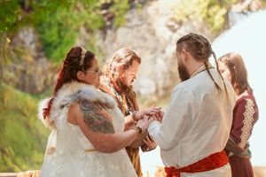 People embrace in joyful group hugs wearing airy white outfits while celebrating outdoors in nature.