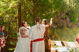 Wedding ceremony in a sunlit forest grove with guests gathered for an outdoor celebration.