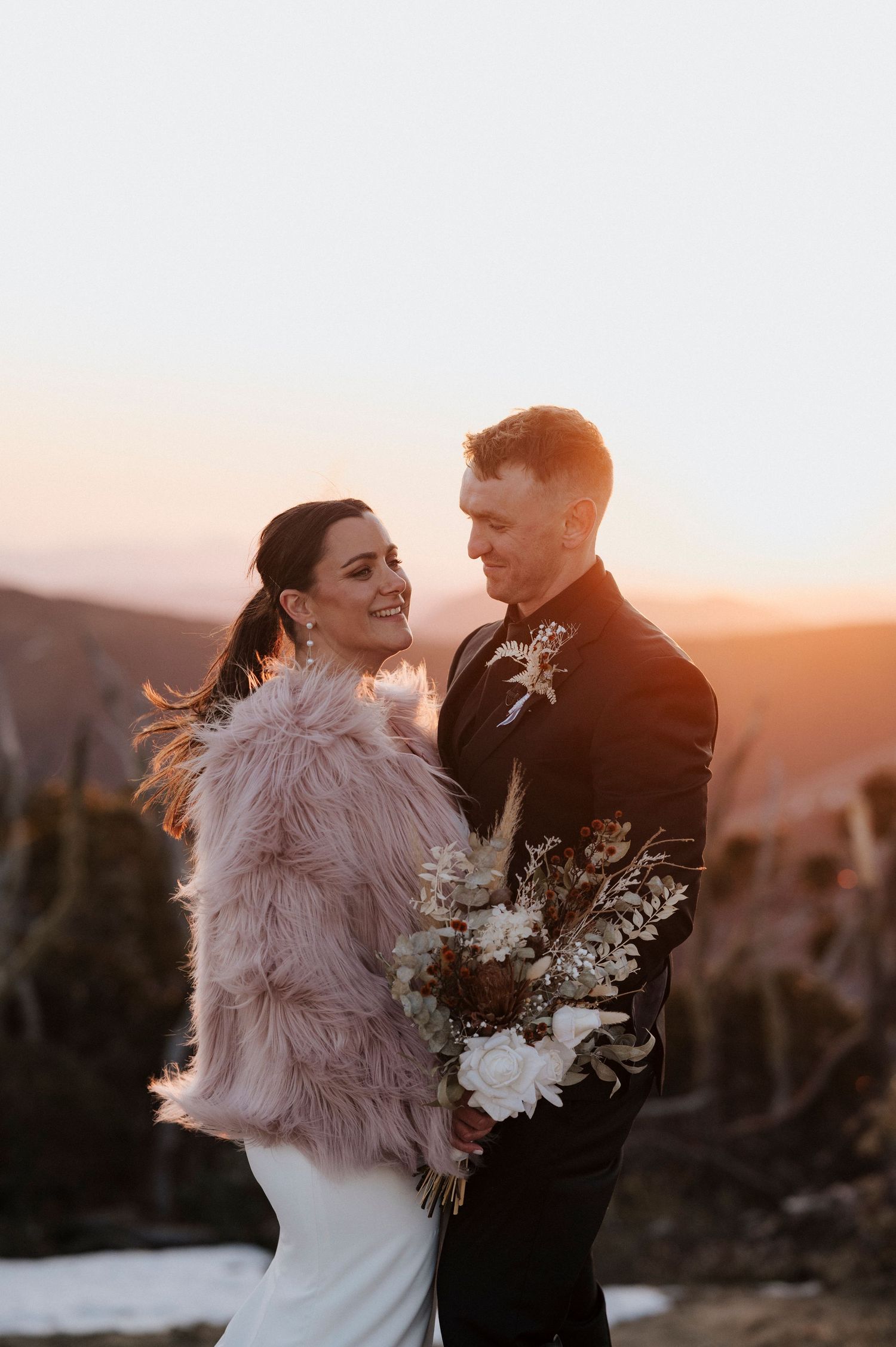 Romantic sunset portrait session in a fur shawl against mountain backdrop.