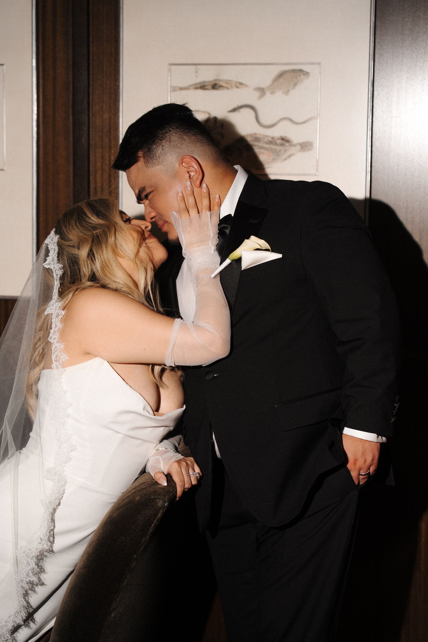 Bride in white gown and groom in black tuxedo share a romantic kiss during their wedding celebration.