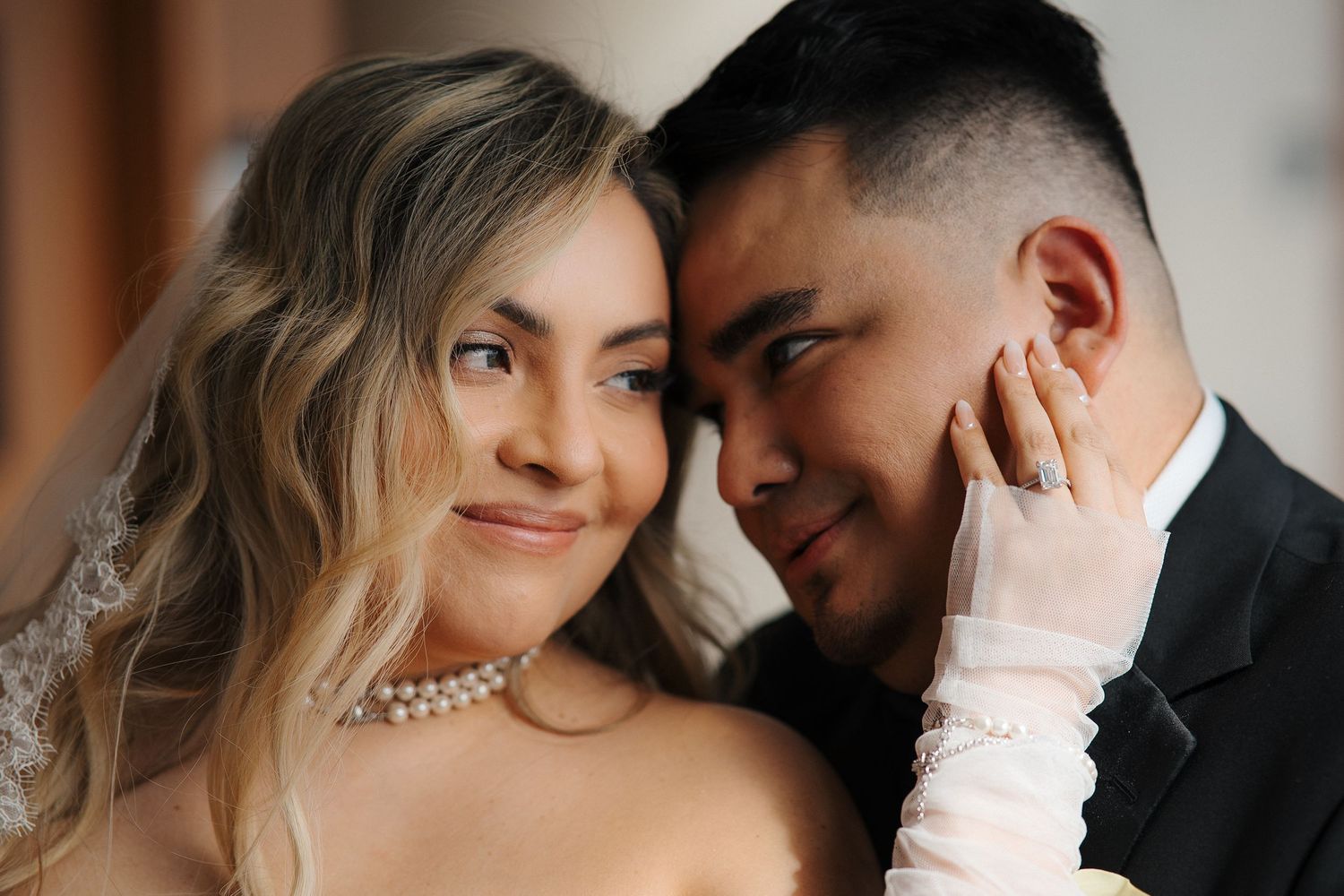 Black and white portrait of couple at formal event with woman in elegant white dress and pearl necklace.
