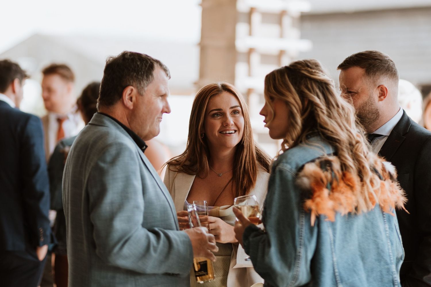 A group of people engaged in lively conversation while holding drinks at a social gathering.