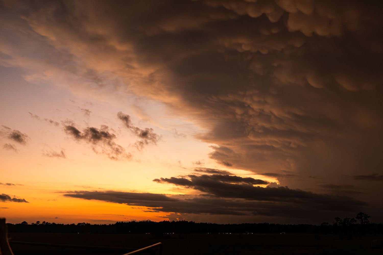 Dramatic sunset sky with dark clouds and golden light on the horizon.