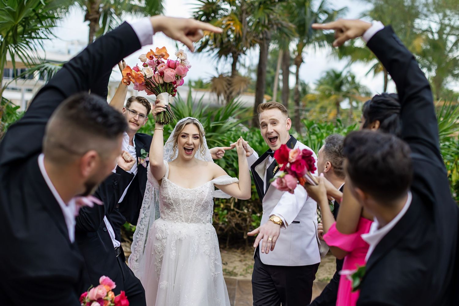 Bride and groom celebrating with their wedding party in the tropical gardens of The Fives Beach Hotel in Playa del Carmen, Mexico.