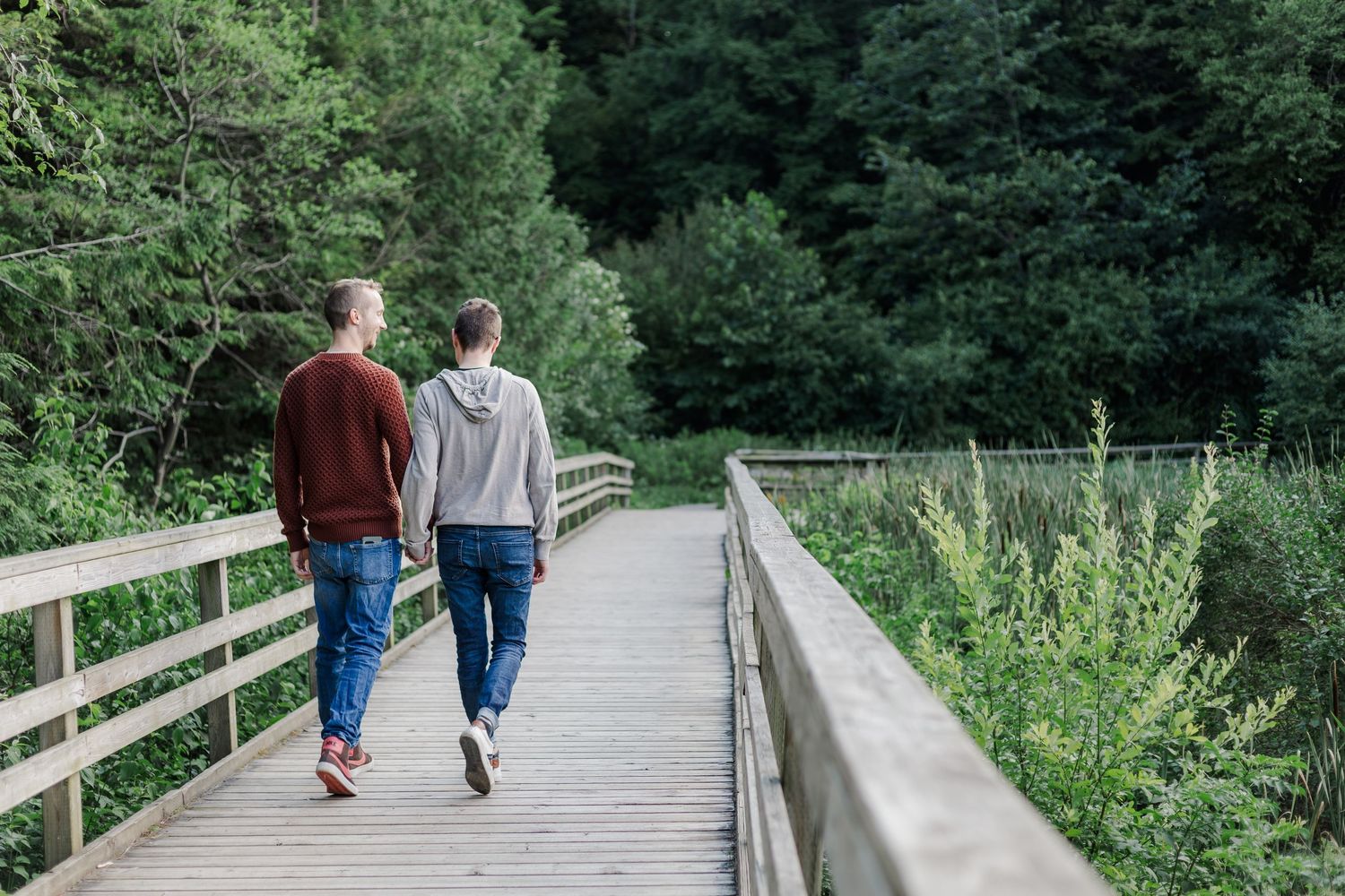 A group of people walking along a winding dirt trail surrounded by lush green vegetation and bushes.