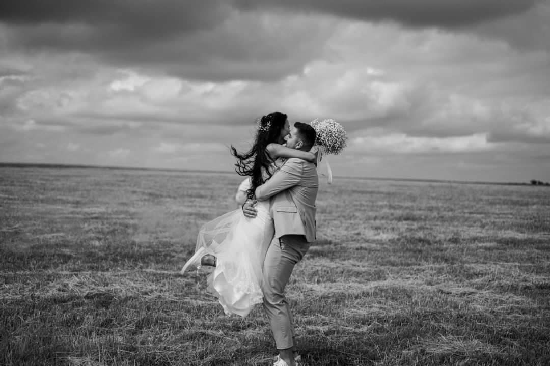 Black and white wedding photos capture intimate moments across a dramatic open landscape.