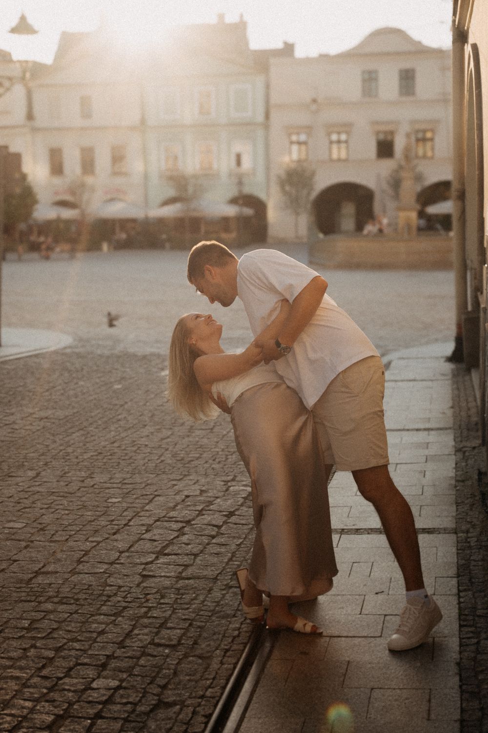 A tender moment captured on cobblestone streets at sunset with warm glowing light.