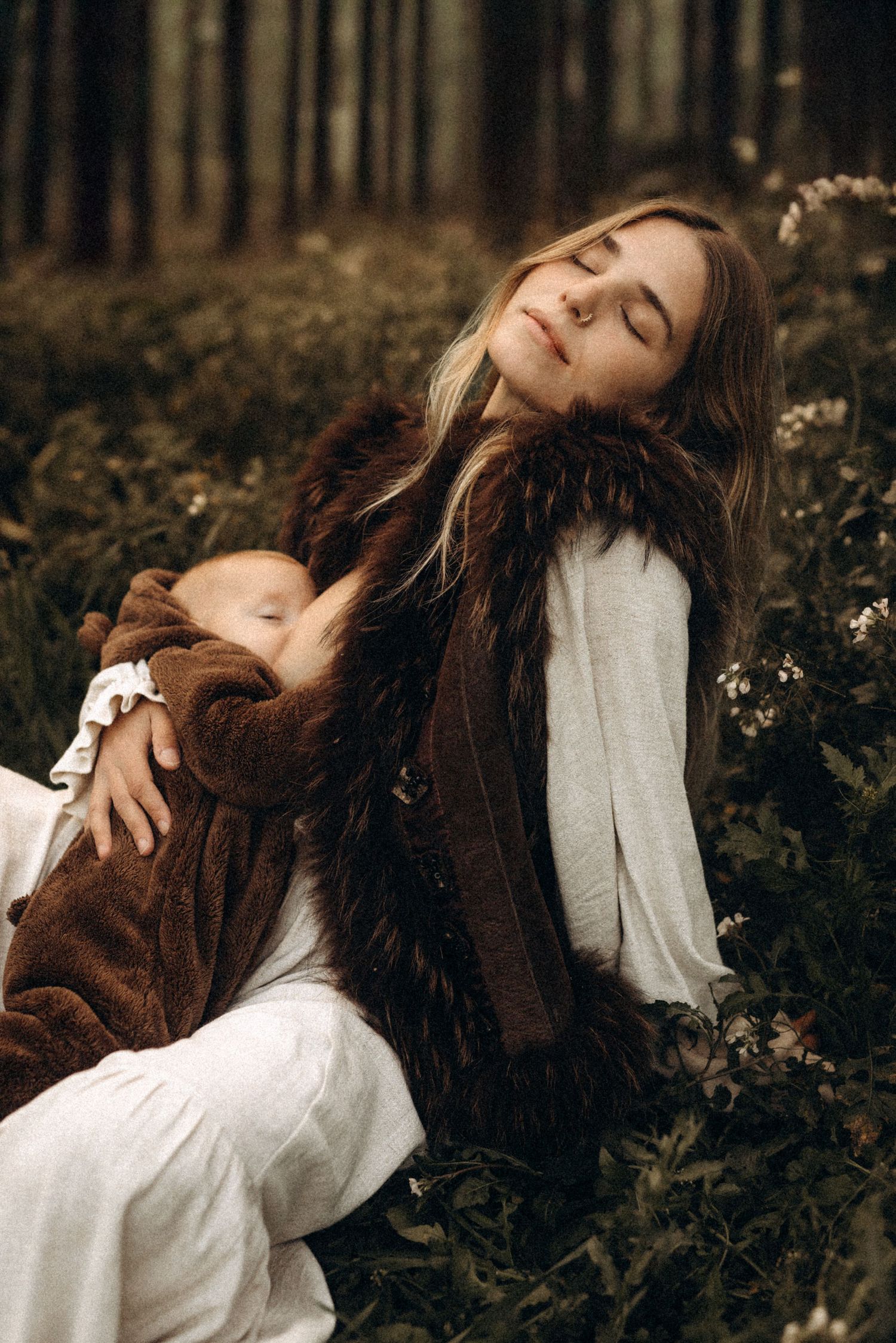 Artistic portrait series showing a mother in white dress and brown jacket lying a moody forest setting. Javea photographer