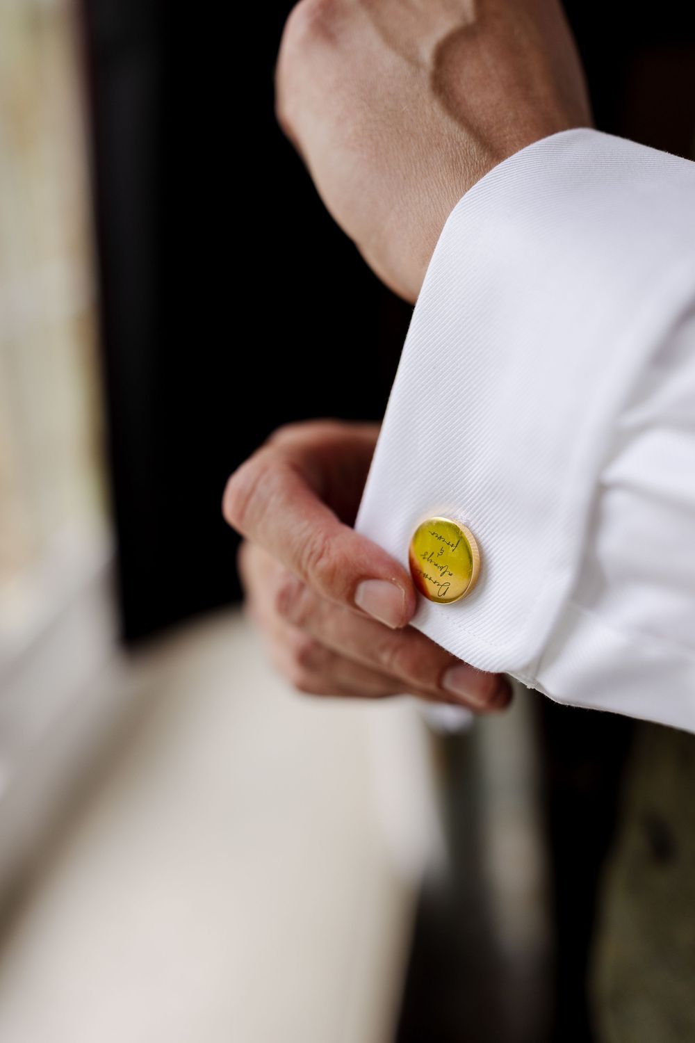 Close-up of a white dress shirt cuff with a golden circular cufflink.