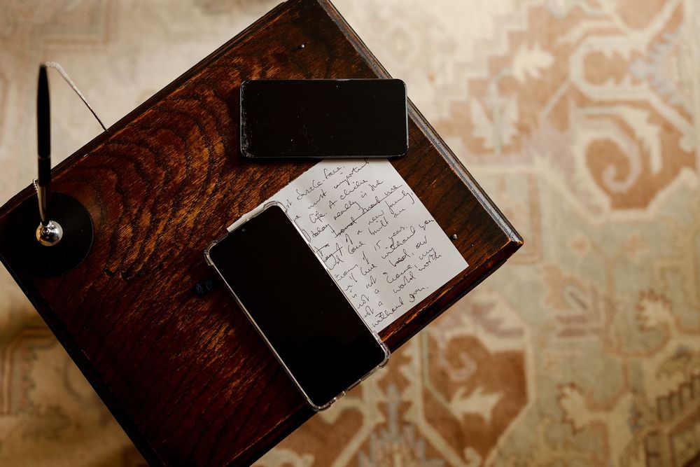 A collection of black leather-bound journals and books arranged on a wooden surface with handwritten pages.