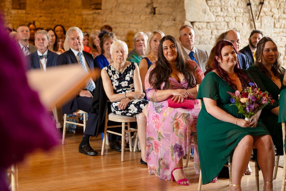 Wedding guests seated in rows at an indoor reception venue.