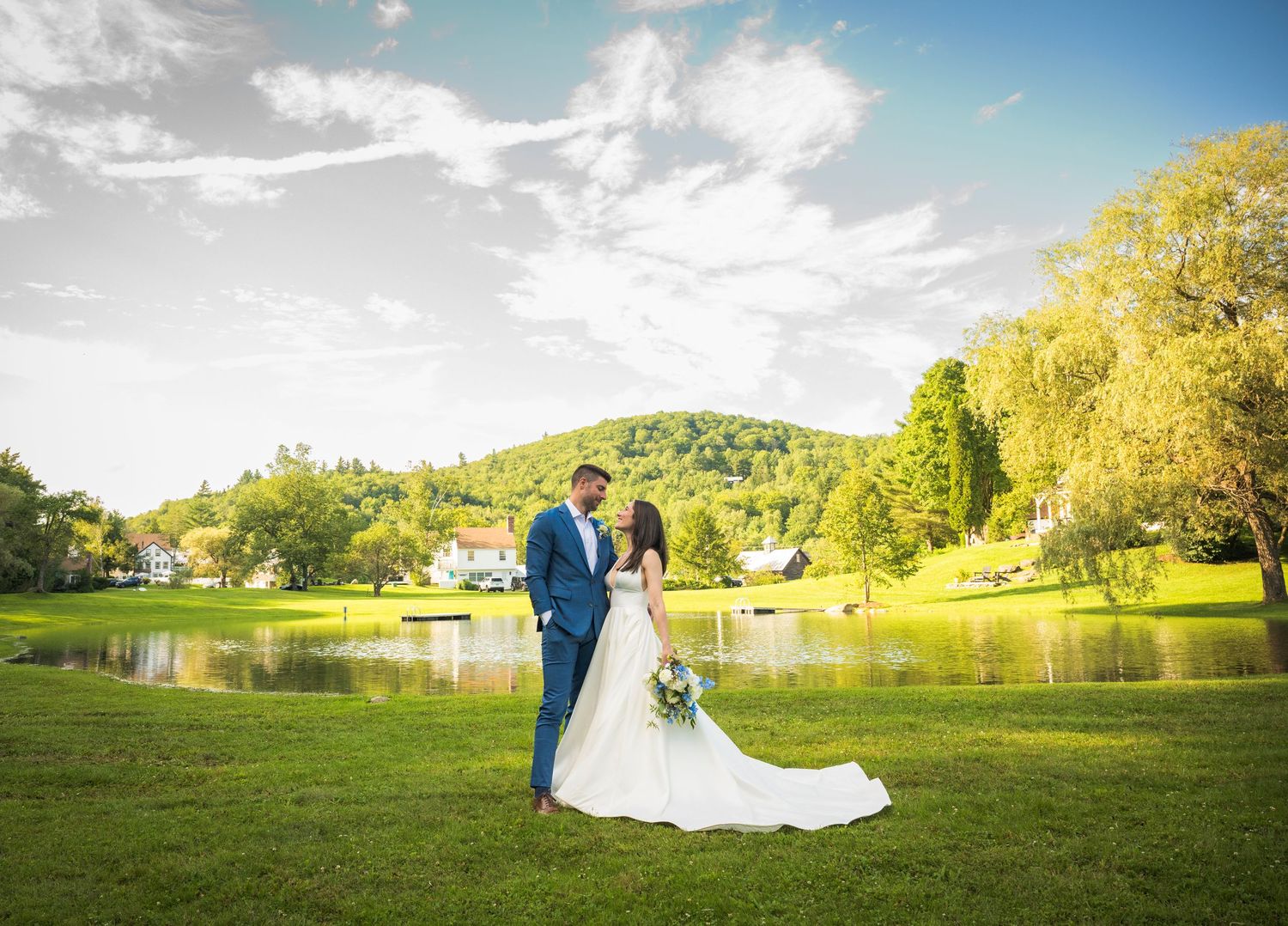 A scenic panoramic view of a green countryside wedding venue with trees and buildings in the background.