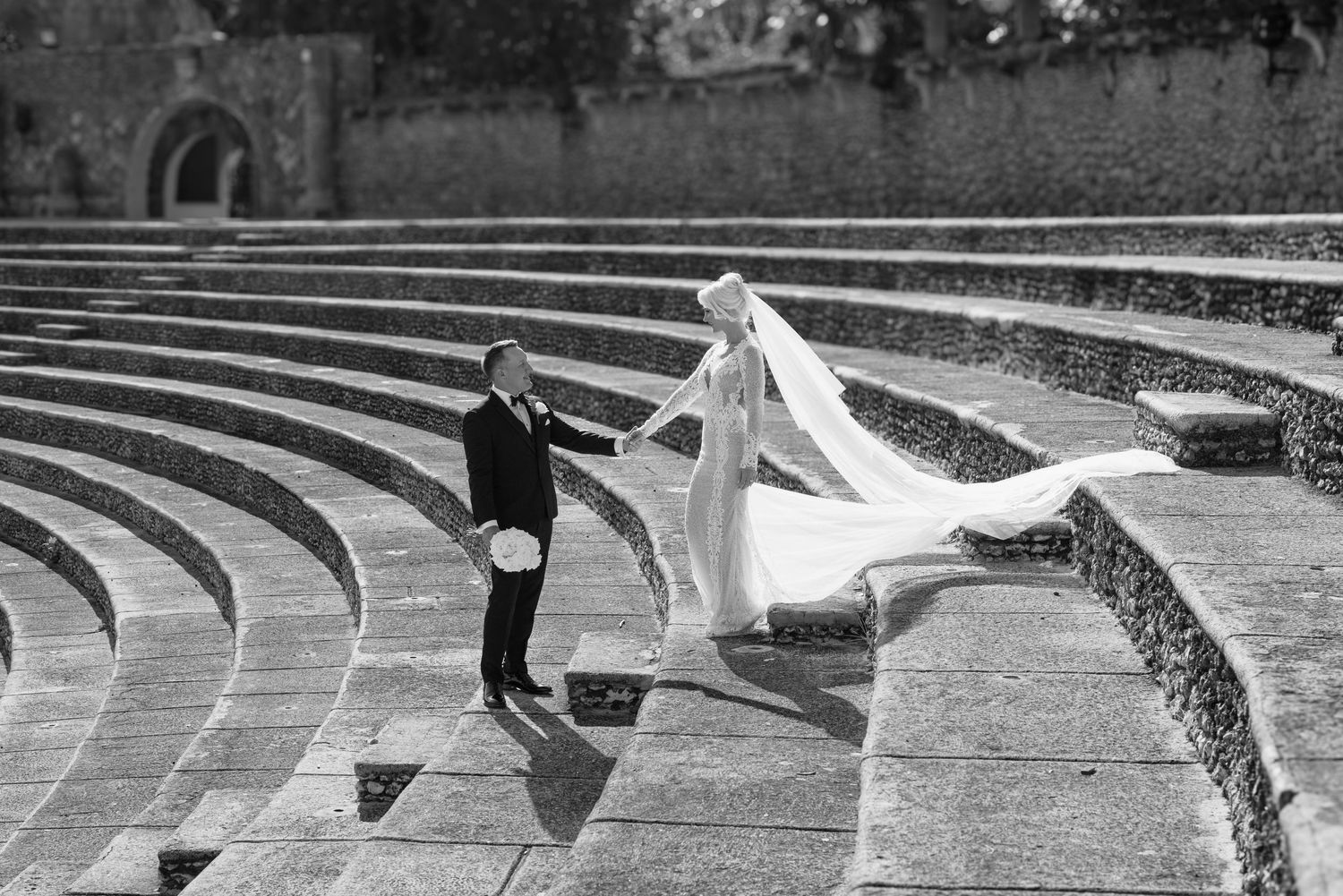 Curved concrete amphitheater seating steps create a geometric pattern in an outdoor venue.