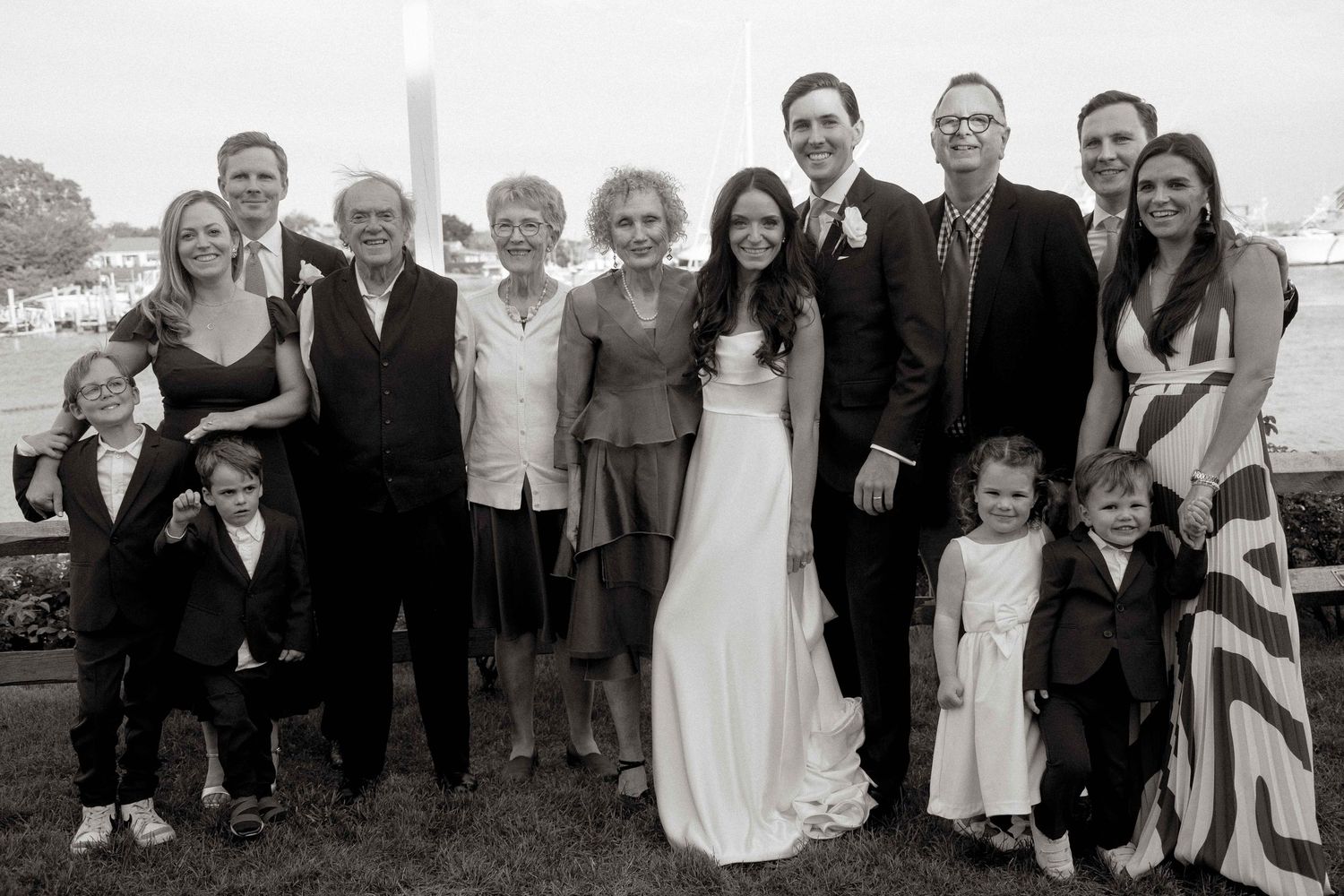 Black and white wedding photo showing a group of people gathered outdoors for a formal family portrait.