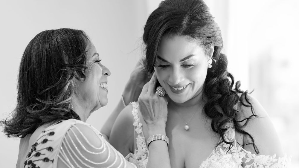 A group of women share joyful laughter and smiles during a wedding preparation moment.