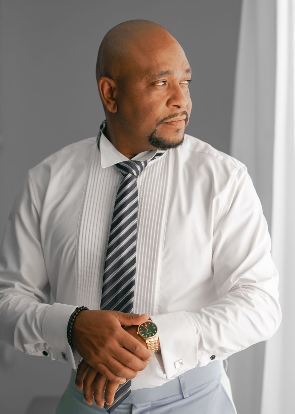 A man in a white dress shirt and striped tie poses in a sequence of casual portrait shots.