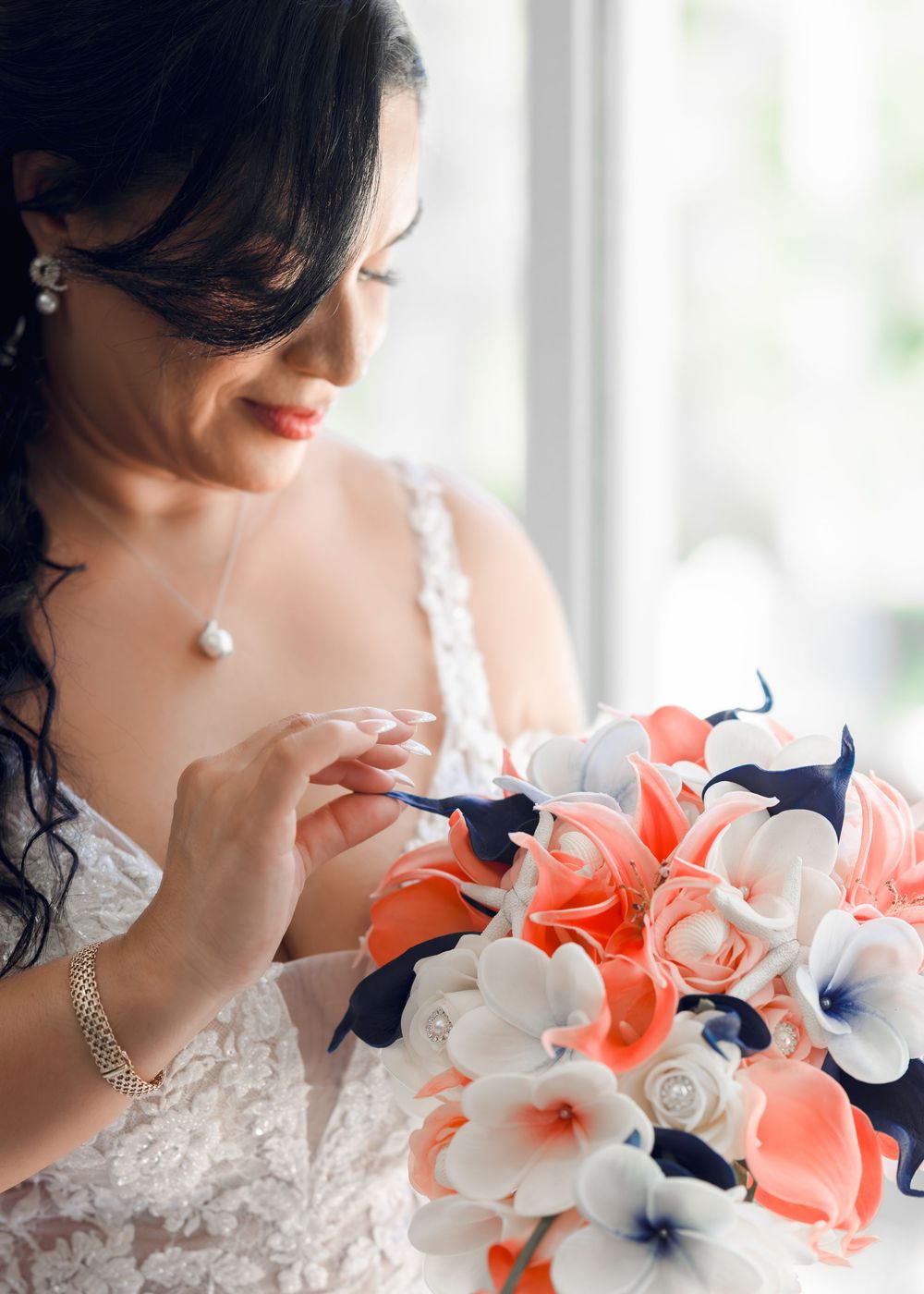 A wedding bouquet in coral, navy and white colors with delicate plumeria flowers and pearls creates an elegant tropical look.