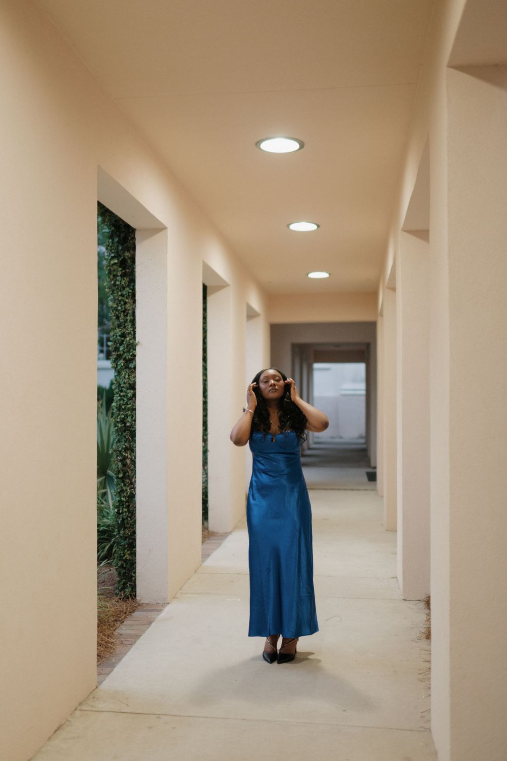 Sequential photos of someone in a blue dress walking through a minimalist white hallway with columns.