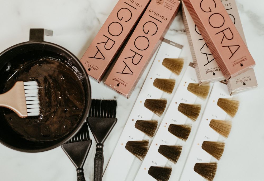 Igora hair color products with mixing bowls, brushes, and hair color swatches on a marble surface.