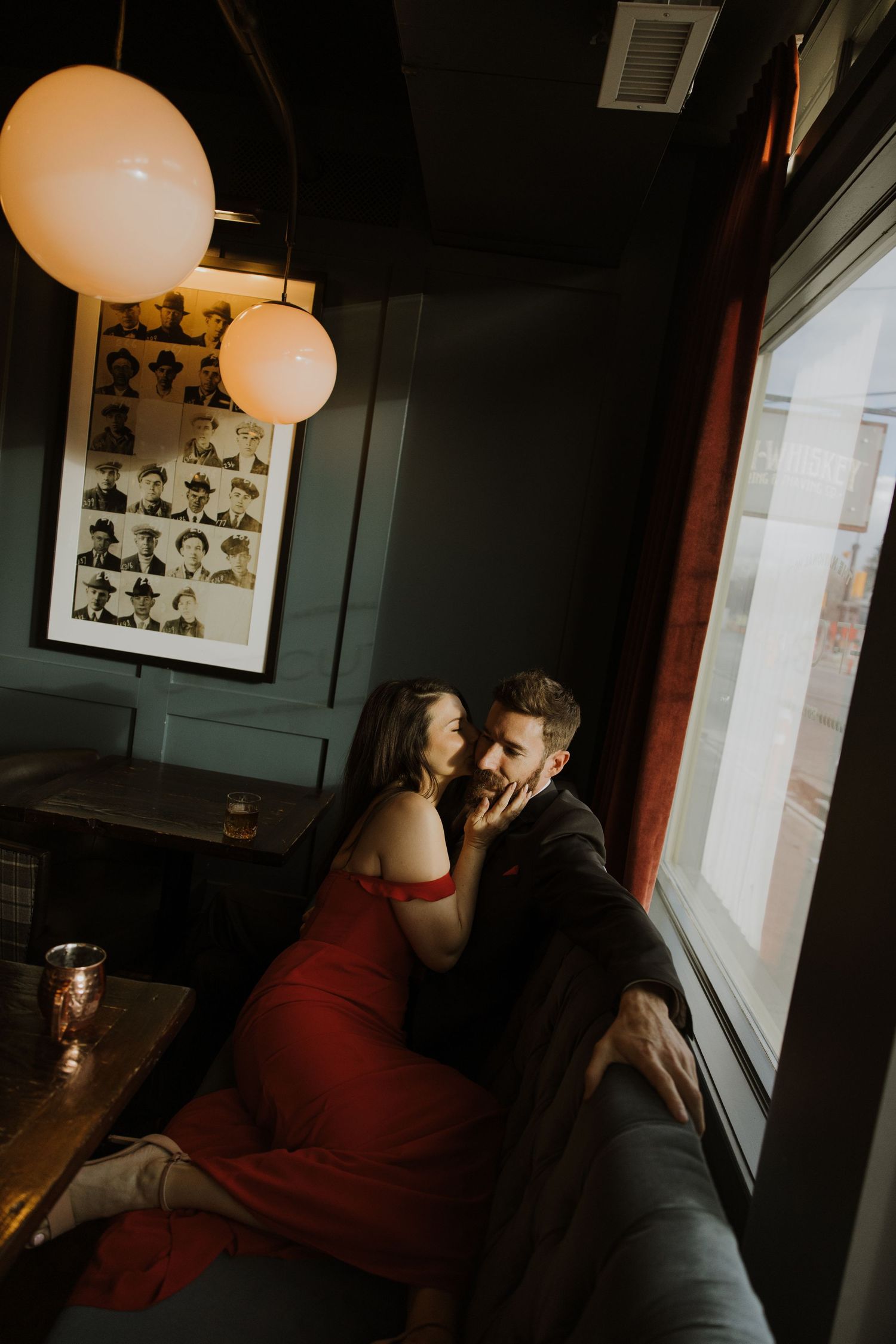 A romantic couple shares an intimate moment in a dimly lit room with paper lanterns and framed artwork.